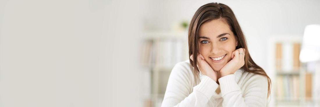 pretty brown haired woman resting her head in her hands against bookshelves in the background