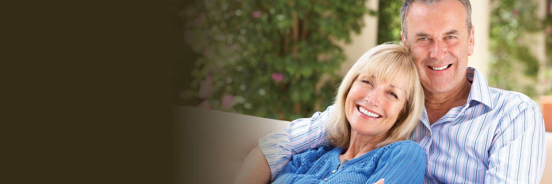 A smiling elderly couple on the couch | dentist baton rouge
