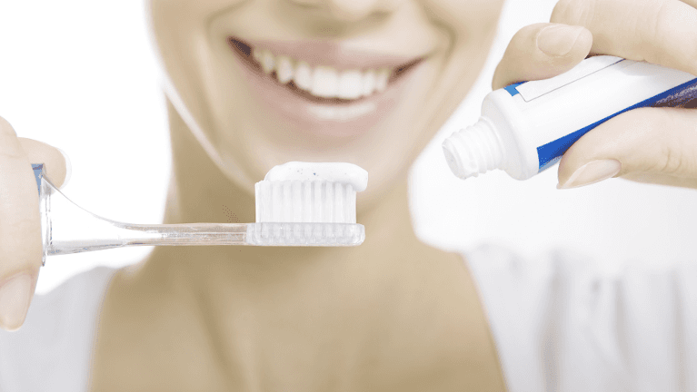putting toothpaste onto a toothbrush