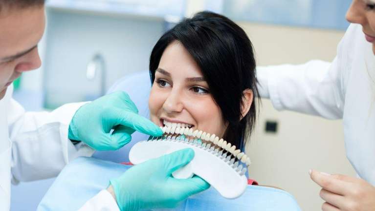 A smiling woman comparing tooth shades | dentist Baton Rouge