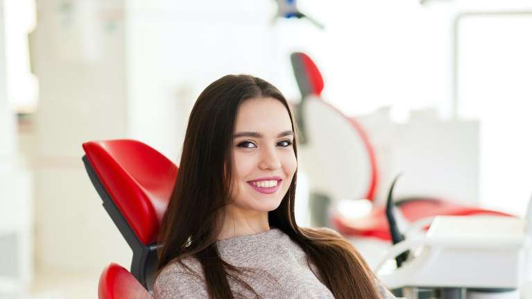 woman sitting in a red dental chair