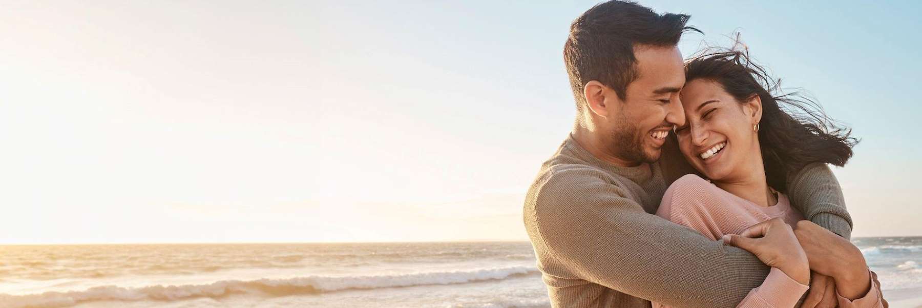 A smiling couple hugging on the beach | teeth whitening Baton Rouge