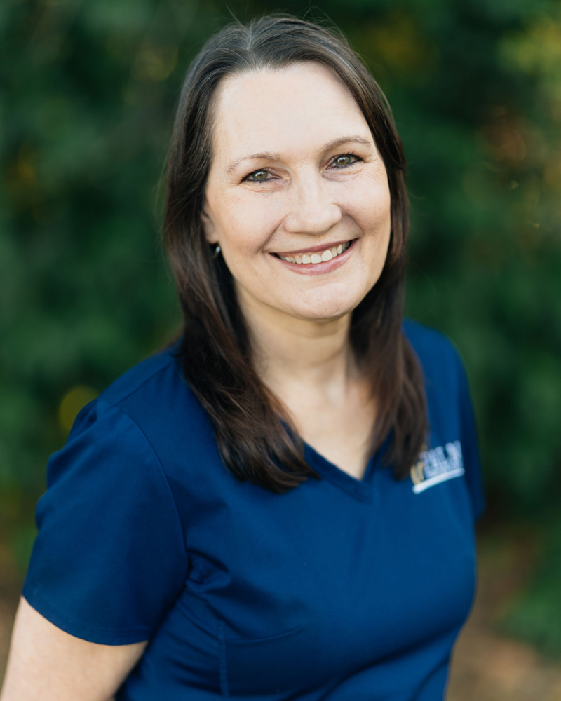 Rita, front office administrator at Palm Family Dentistry, smiling warmly in navy scrubs outdoors